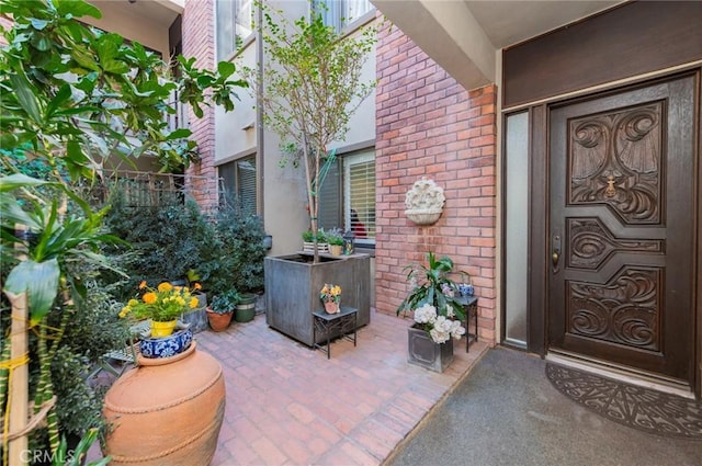 property entrance featuring brick siding and a patio