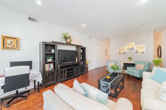 living room with wood finished floors, visible vents, and recessed lighting