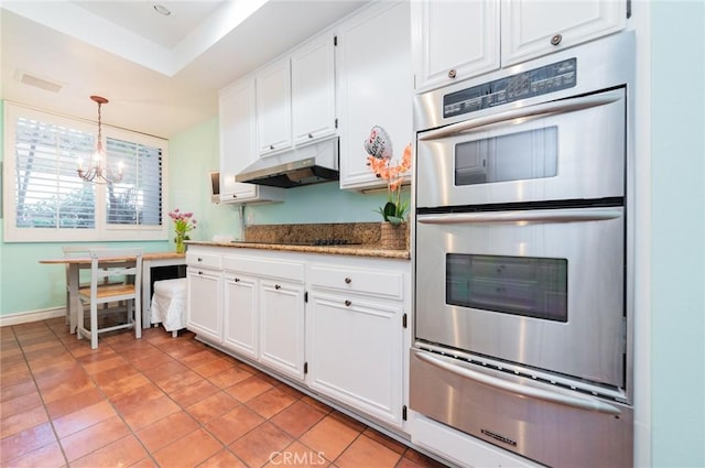 kitchen with double oven, under cabinet range hood, white cabinets, a warming drawer, and decorative light fixtures