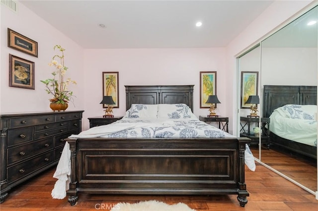 bedroom with a closet, wood finished floors, visible vents, and recessed lighting