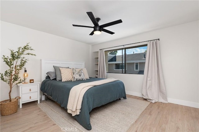 bedroom with baseboards, ceiling fan, and light wood-style floors