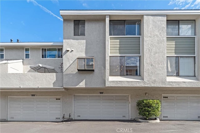 back of property with an attached garage and stucco siding