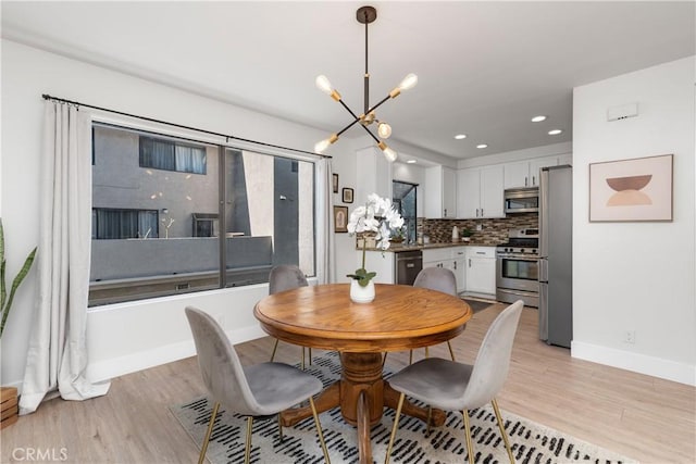 dining room with recessed lighting, light wood-style flooring, baseboards, and an inviting chandelier