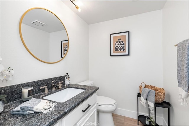 bathroom with toilet, baseboards, wood finished floors, and vanity