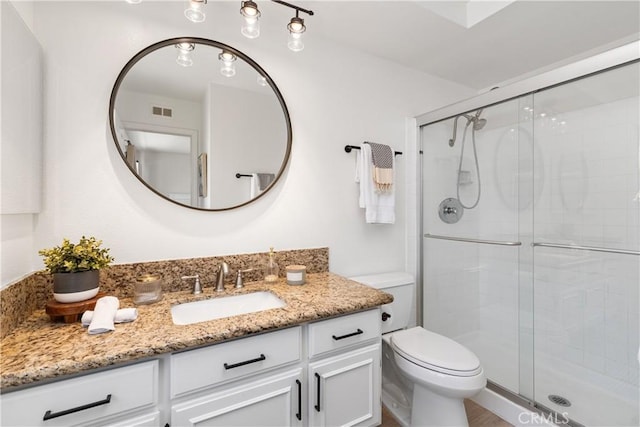 full bathroom featuring toilet, vanity, a shower stall, and visible vents