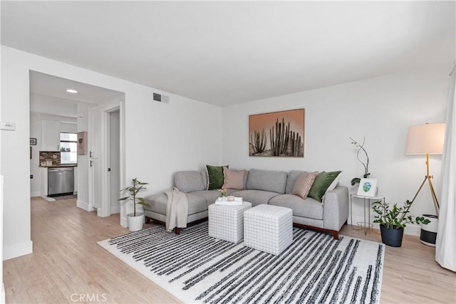 living area featuring light wood-type flooring, visible vents, and baseboards