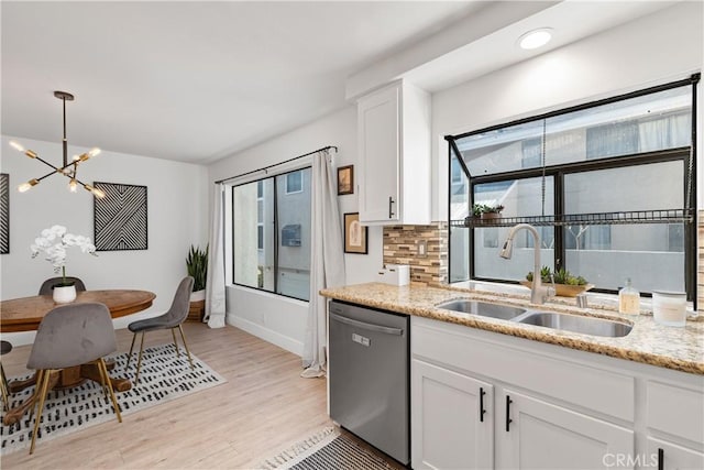 kitchen featuring light stone counters, decorative light fixtures, white cabinetry, a sink, and dishwasher