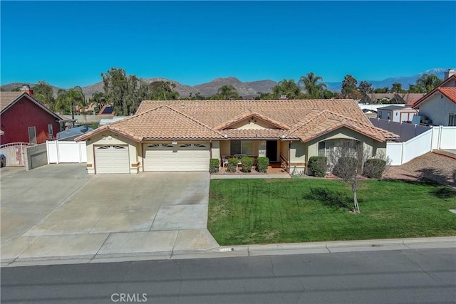 view of front of property with an attached garage, a mountain view, a tiled roof, and a front lawn