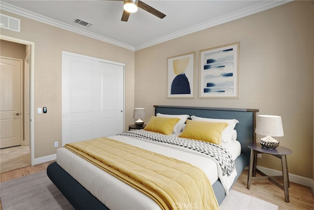 bedroom with light wood-style floors, crown molding, visible vents, and a closet