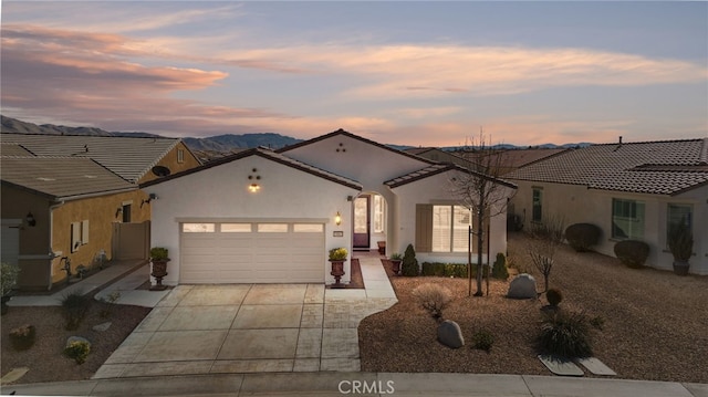 mediterranean / spanish home with driveway, an attached garage, a tile roof, and stucco siding