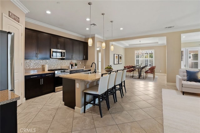 kitchen featuring a breakfast bar, stainless steel appliances, tasteful backsplash, visible vents, and a sink