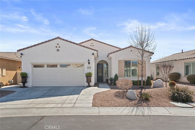 mediterranean / spanish house featuring a garage, driveway, a tiled roof, and stucco siding