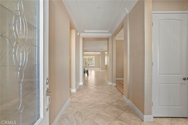 corridor with light tile patterned flooring, crown molding, and baseboards