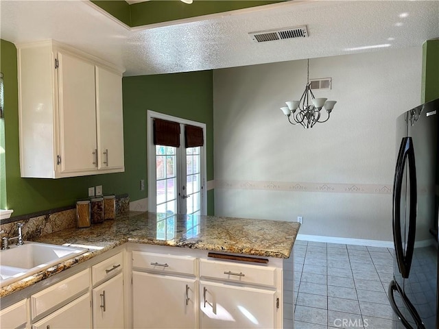 kitchen with a peninsula, white cabinetry, and freestanding refrigerator