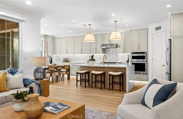 living room featuring ornamental molding, recessed lighting, visible vents, and light wood finished floors