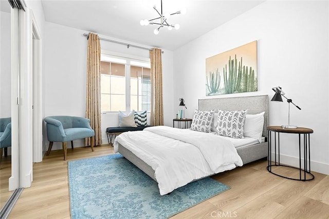 bedroom with light wood finished floors, a closet, baseboards, and a notable chandelier