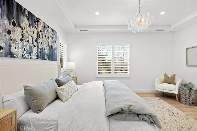 bedroom with visible vents, a raised ceiling, wood finished floors, and recessed lighting