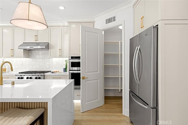 kitchen featuring visible vents, decorative backsplash, appliances with stainless steel finishes, under cabinet range hood, and a sink