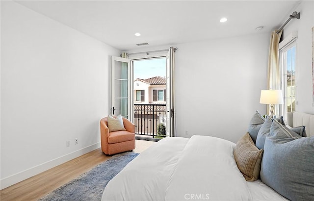 bedroom featuring multiple windows, light wood-type flooring, visible vents, and baseboards