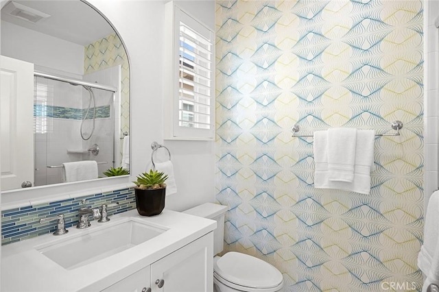 full bath with tasteful backsplash, visible vents, toilet, a shower with shower door, and vanity