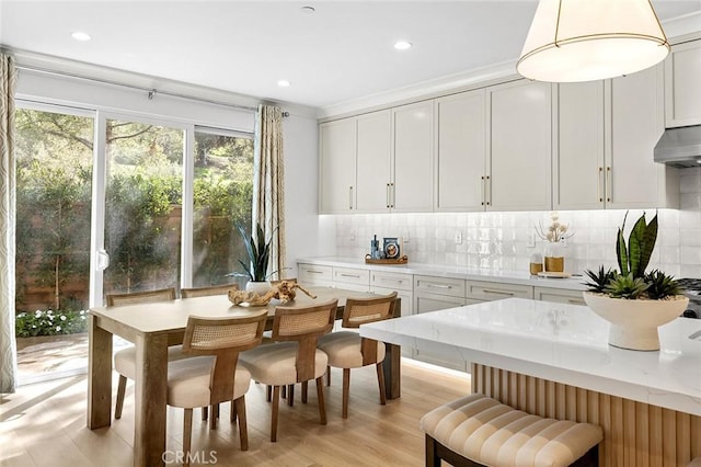 kitchen featuring under cabinet range hood, tasteful backsplash, white cabinetry, and light wood finished floors