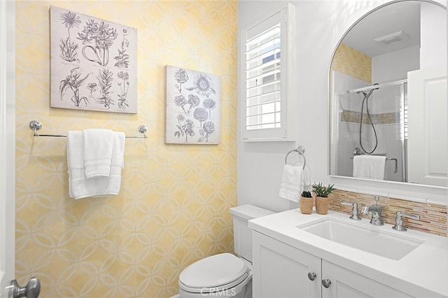 bathroom featuring visible vents, toilet, a stall shower, vanity, and wallpapered walls