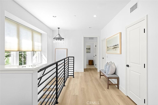 hallway with recessed lighting, visible vents, light wood-style flooring, an upstairs landing, and baseboards