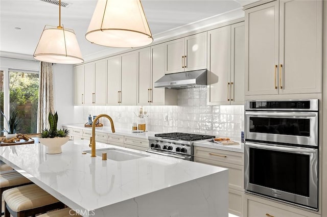 kitchen featuring double oven, under cabinet range hood, stove, a sink, and tasteful backsplash