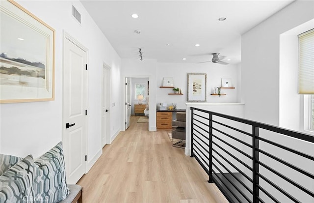 hallway featuring light wood finished floors, recessed lighting, visible vents, and an upstairs landing