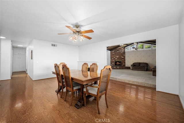 dining area with ceiling fan, a fireplace, visible vents, and wood finished floors