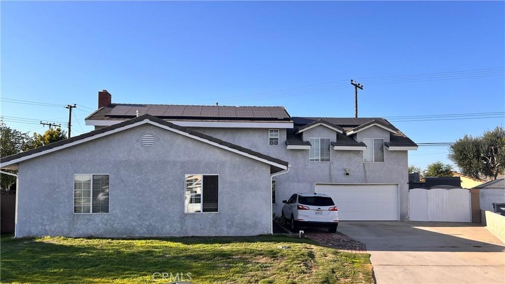 view of front of property with driveway, solar panels, a gate, and stucco siding