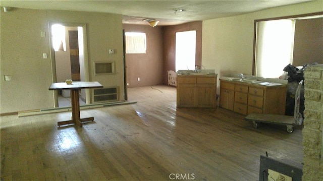 interior space with light countertops, a stone fireplace, brown cabinetry, and wood finished floors