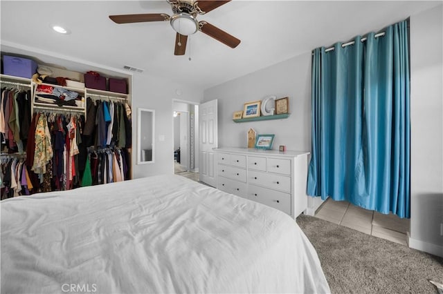 bedroom featuring a ceiling fan, light colored carpet, visible vents, and light tile patterned floors