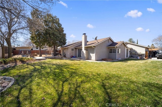 rear view of house featuring a patio, a fenced backyard, a yard, stucco siding, and a chimney