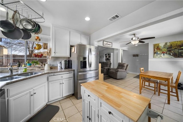 kitchen featuring light tile patterned floors, a sink, visible vents, white cabinets, and stainless steel fridge