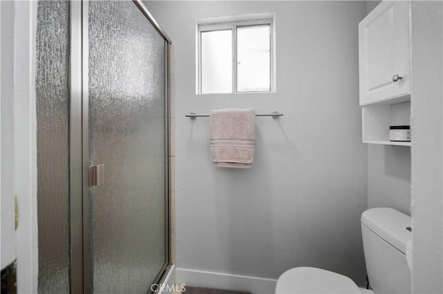 full bath featuring baseboards, a shower with shower door, and toilet