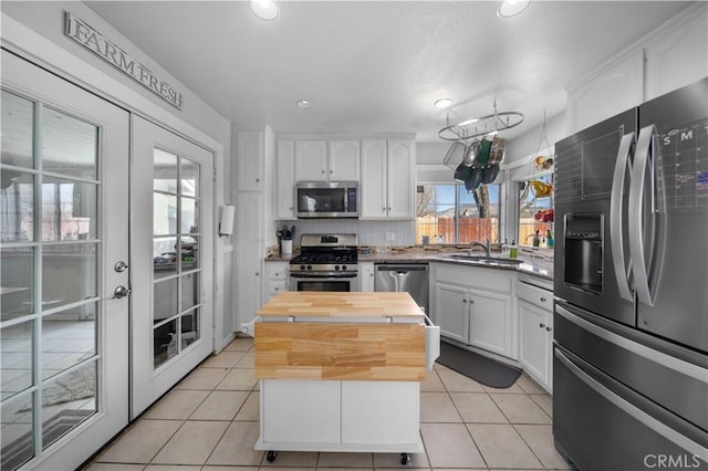 kitchen featuring light tile patterned floors, appliances with stainless steel finishes, wood counters, and white cabinets