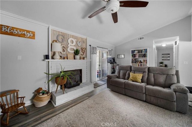 living area with visible vents, ornamental molding, wood finished floors, vaulted ceiling, and a fireplace