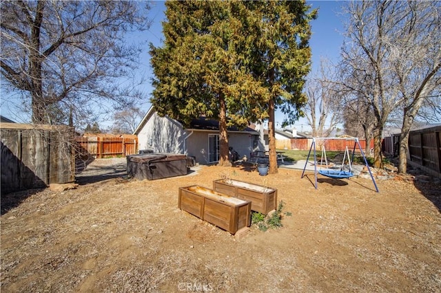 view of yard featuring a playground, a fenced backyard, and a garden