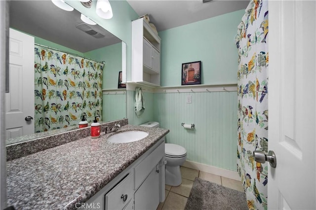 bathroom featuring toilet, tile patterned flooring, vanity, and wainscoting