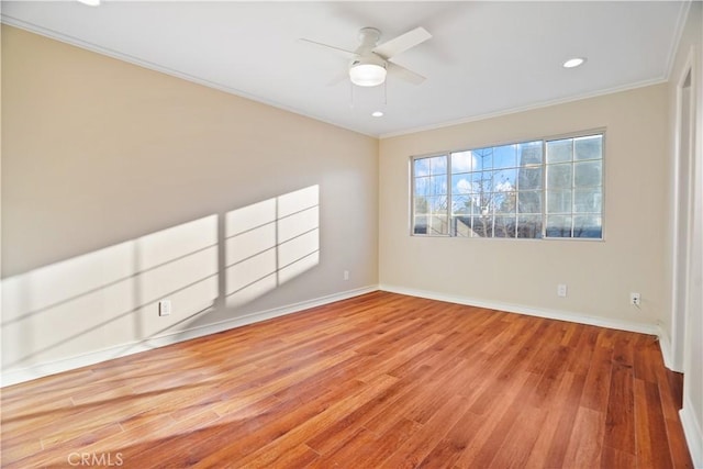 empty room with ceiling fan, crown molding, baseboards, and wood finished floors