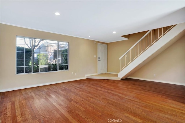 interior space featuring crown molding, wood finished floors, stairs, and baseboards