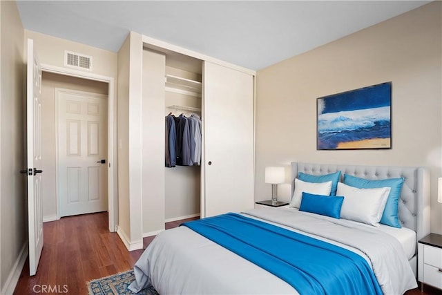 bedroom featuring baseboards, visible vents, a closet, and wood finished floors