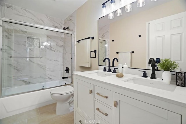 full bathroom with enclosed tub / shower combo, double vanity, a sink, and toilet