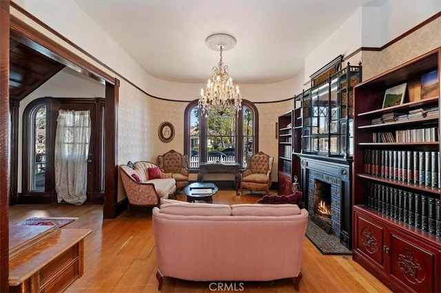 living area featuring a high end fireplace, light wood-style flooring, and an inviting chandelier