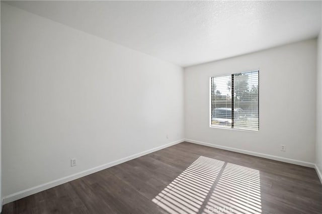 unfurnished room with dark wood-style floors and baseboards