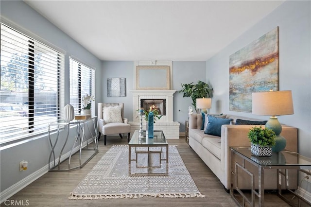 living area with a brick fireplace, baseboards, and wood finished floors