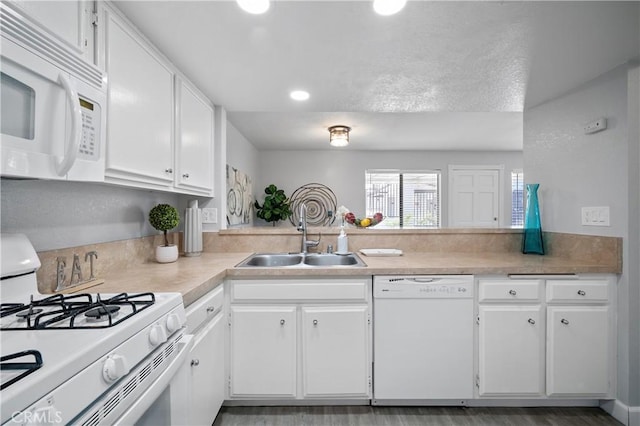 kitchen featuring white appliances, white cabinets, a sink, and light countertops