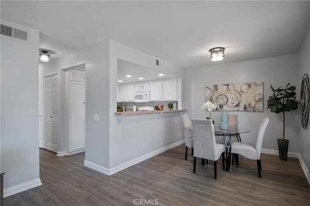 dining space with dark wood-style floors, visible vents, and baseboards