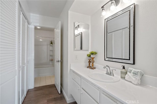 bathroom with washtub / shower combination, wood finished floors, and vanity